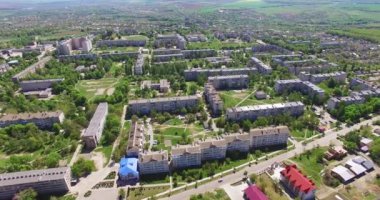 Konut alanındaki çok katlı apartman blokları. Evlerin arasında bir sürü yeşil ağaç yetişiyor. Arkaplanda nehir.