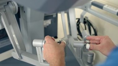 Doktorun elleri robotik ekipmanların saplarını yavaşça hareket ettiriyor. Tıbbi profesyoneller tarafından işletilen gelecekçi Da Vinci robotu. Kapat..