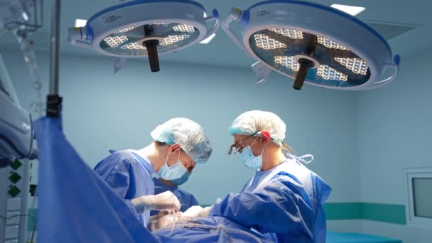 Drużyna Chirurgów Stojąca Pod Wielkimi Lampami Nad Pacjentem Sali Operacyjnej — Wideo stockowe
