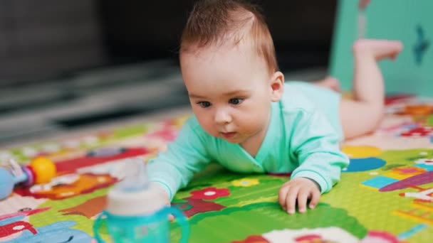 髪の毛をまとった赤ん坊の少年が瓶に這い上がった 面白い小さな子供は 床のカラフルなマットによって意図的に移動します — ストック動画
