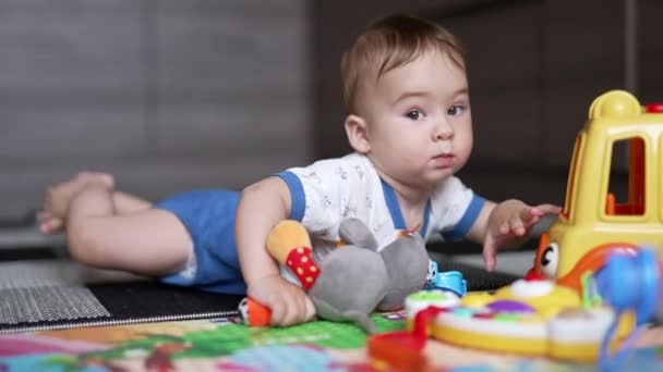 Милый Малыш Лежащий Полу Подползает Ближе Своим Игрушкам Любимый Ребенок — стоковое видео