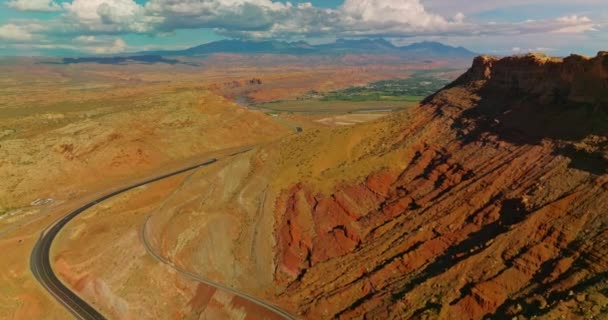犹他州国家公园的岩石 沙漠和绿色山谷 无人机在峡谷脚下的高速公路上飞行 空中展望 — 图库视频影像