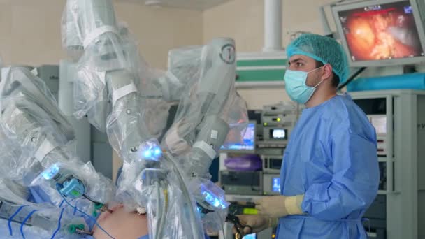 Dokter Pria Muda Berdiri Dekat Pasien Yang Dioperasikan Oleh Robot — Stok Video