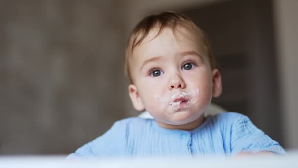 スプーンからお粥を食べるかわいい子 母は赤ちゃんにお粥を与え 子供の顔からお粥を取り出します — ストック動画