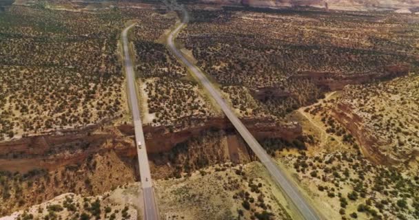 犹他州国家公园荒无人烟的土地上的巨大沟渠 两座桥连接战壕边缘和经过的汽车 空中景观 — 图库视频影像
