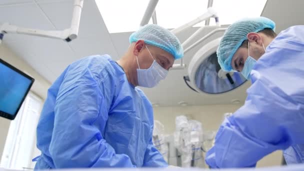 Operasyonda Çalışan Iki Erkek Tıp Uzmanı Modern Ameliyathanede Maskeli Şapkalı — Stok video