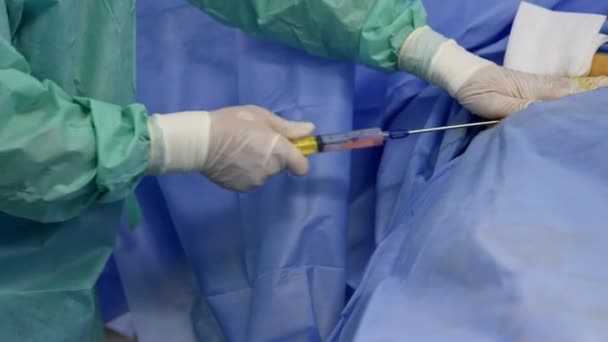 医生的手戴着乳胶手套 用长针把巨大的注射器塞入病人的腹部 在现代医院工作的专业外科医生 — 图库视频影像