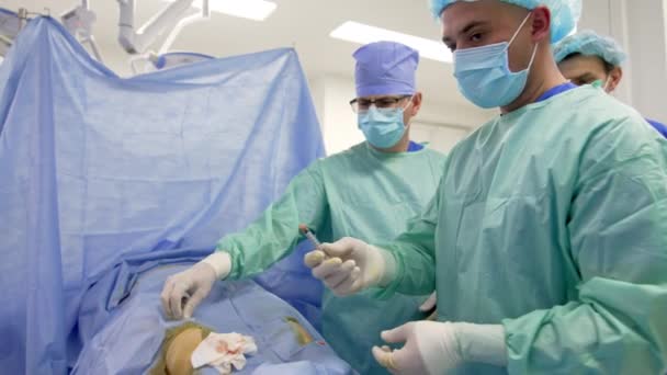 在手术室工作的一组外科医生 医生给病人注射 并把注射器交给助手 — 图库视频影像