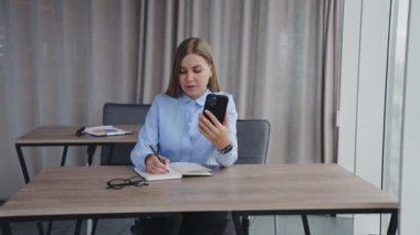 Genç iş kadını not defterine bir şeyler yazıyor. Gülümseyen bayan ileriye bakan bir şeyin üzerinde düşünüyor. Kapat..