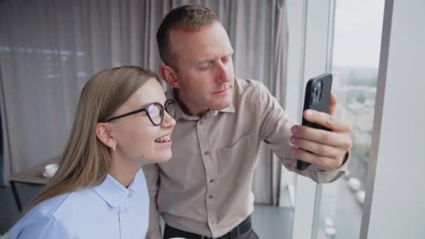 사무실에서 남자와 동료는 자신의 전화에 무언가를 수있는 여성의 안경을 가지고 — 비디오