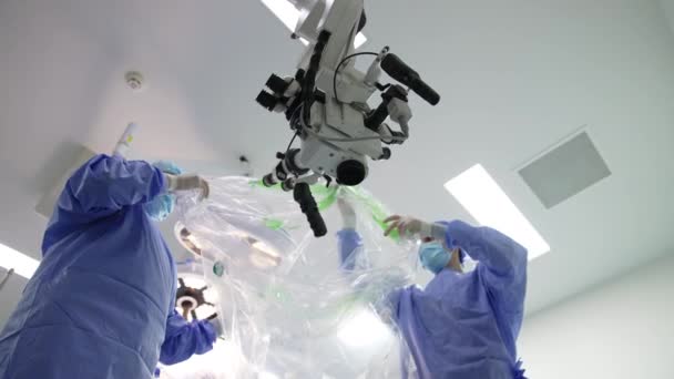 Δύο Γιατροί Καλύπτουν Ισχυρό Μικροσκόπιο Που Κρέμεται Στο Χειρουργείο Πλαστικό — Αρχείο Βίντεο
