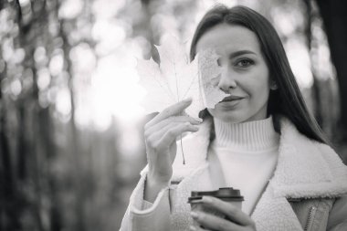 Güzel genç bir kadın elinde yaprak tutuyor ve ona bakıyor..