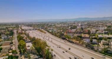 Arabaları Los Angeles, California, ABD 'deki çok şeritli otoyollara süratle taşıdı. Arka planda inanılmaz açık mavi gökyüzü. İHA görüntüleri yükseliyor.