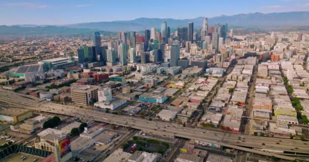 ロサンゼルス カリフォルニア アメリカの低層ビルの中に立っている有名な高層ビル 昼間はフリーウェイで移動する車がたくさんあります エアリアルビュー — ストック動画
