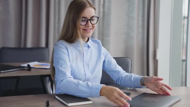 オフィスで働き始める幸せな若い金髪の女性 メガネの女性は キーボード上のノートパソコンとタイプを開きます — ストック動画