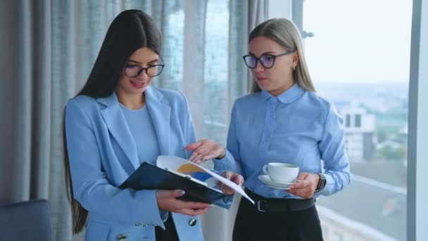 同事之间的非正式沟通 两名女雇员站在办公室里谈论文件 — 图库视频影像