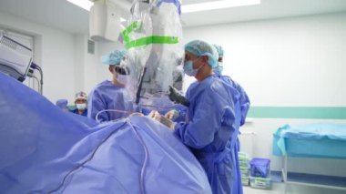 Tıp uzmanları güçlü mikroskop ameliyatına bakıyorlar. Cerrahlar takımından modern operasyonel tiyatroya olan uzaklık.
