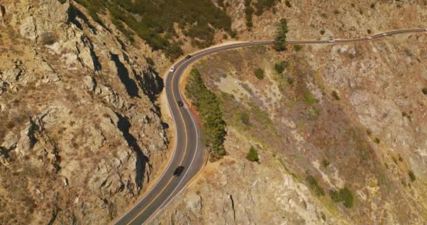 在多山的风景中 车辆来回穿梭的鲜活的道路 从空中看 在阳光灿烂的日子里 巨大的山 绿意盎然 — 图库视频影像