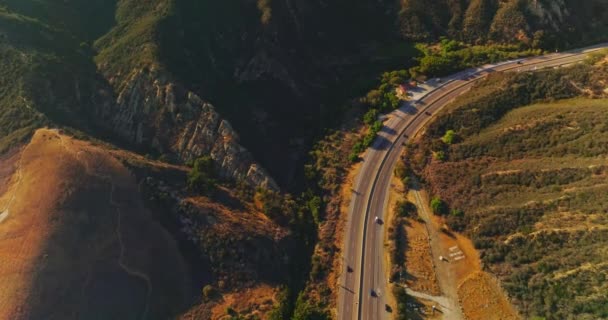 阳光灿烂的日子 高速公路上的山区 用移动的汽车把无人驾驶飞机的镜头扔到路上空中景观 — 图库视频影像