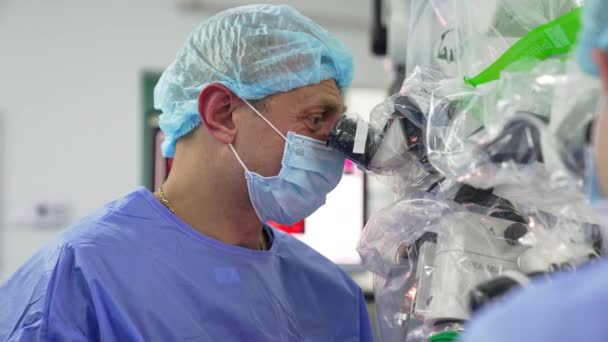 Homme Chirurgien Adulte Masque Casquette Regarde Attentivement Dans Microscope Commentant — Video