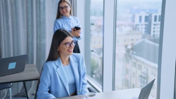 職場の同僚同士のコミュニケーション 明るいモダンオフィスにいる2人の女性従業員が陽気で笑顔で話す — ストック動画