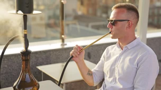 Νεαρός Ξεκουράζεται Στο Μπαρ Χούκα Άντρας Γυαλιά Ηλίου Καπνίζει Shisha — Αρχείο Βίντεο