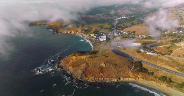 阳光充足的岩石海岸线 顶部有房屋和公路 浓雾弥漫在城市里 空中展望 — 图库视频影像
