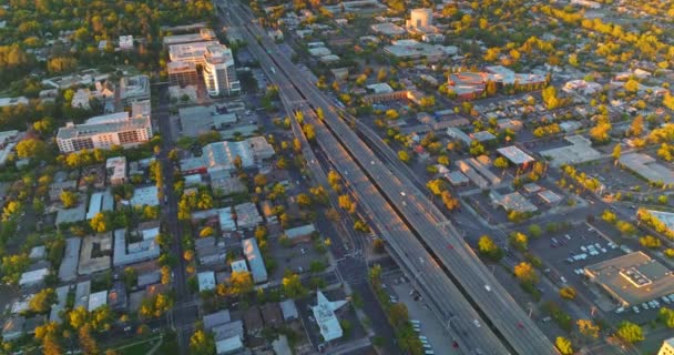 マルチレーンは大都市に沿って2本の道路を走っている 太陽を設定する光線の緑の都市パノラマ エアリアルビュー — ストック動画