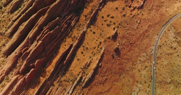 奇妙な形をした岩に沿って道路を走る車 アメリカ合衆国ユタ州のキャニオンとオレンジ砂漠 エアリアルビュー — ストック動画