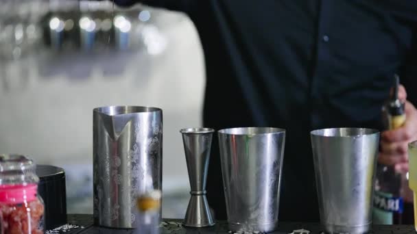 バーでカクテルを作るために使用される金属製のカップとビーバー 黒いシャツの男性は 赤い飲み物で金属瓶を満たしています クローズアップ — ストック動画