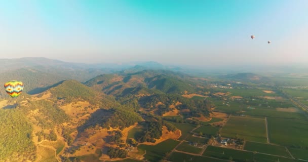 三个气球高高的在空中 在薄雾和青翠的山谷中 老鹰在美丽的群山上空飞翔 蓝天背景 — 图库视频影像