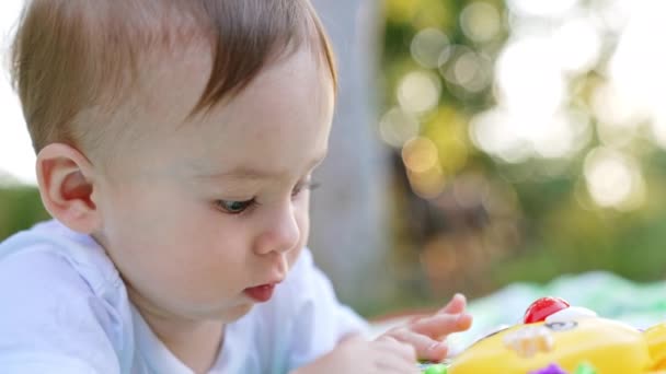 赤ちゃんの顔は忙しく 明るい黄色の玩具に興味を持っています クローズアップ バックグラウンド — ストック動画