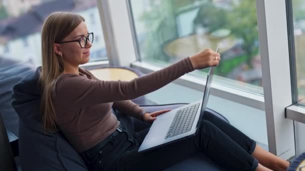 안경을 여자는 노트북을 엽니다 여성은 편안한 의자에 그녀의 컴퓨터에 시작합니다 — 비디오