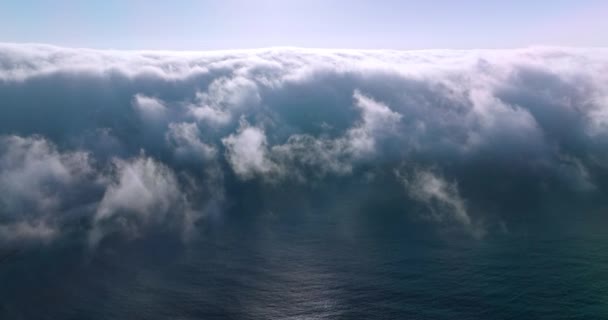 濃い霧で覆われている青い海水 明るい太陽が曇りの上に輝いています エアリアルビュー — ストック動画