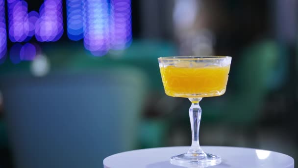 玻璃杯加美味佳肴 旋转桌子上的橙酒鸡尾酒 靠近点模糊的背景 — 图库视频影像
