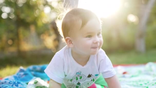 庭で遊んでいる可愛い赤ちゃん 明るい太陽の光の中でかわいい子供たち クローズアップ ブラーレッド バックドロップ — ストック動画