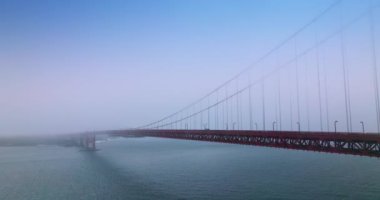 Golden Gate Köprüsü 'nün inanılmaz inşaatı boyunca uçuyor. Yoğun beyaz siste kısmen ünlü bir simge. Yan görünüm.