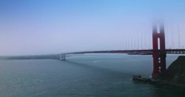 Ünlü San Francisco tarihi Golden Gate köprüsü. Köprünün üst kısımları sisli. Köprünün altından tekne geçiyor..