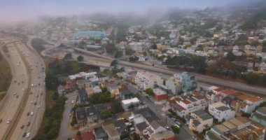 San Francisco 'daki karmaşık yollar trafiği yoğun. Şehir panoraması yavaş yavaş beyaz sisle kaplanıyor. Hava görünümü.