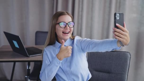 年轻的办公室职员在电话里自私自利微笑的女士用她的手做手势和拍照 模糊的背景 — 图库视频影像
