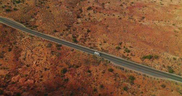在美国犹他州荒无人烟的土地上 一辆白色拖车驶过马路 在沙质的土地上和峡谷的圆形岩石上拍摄的无人机镜头 前面的视图 — 图库视频影像