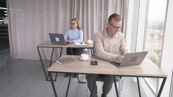 ラップトップの前に座っているオフィスで働く若い中年のチームメイト 眼鏡をかけている男性社員の肖像画 — ストック動画