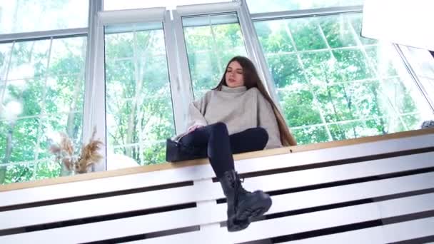 Uzun Siyah Saçlı Kalın Kazak Giyen Pencere Pervazında Oturan Üzgün — Stok video