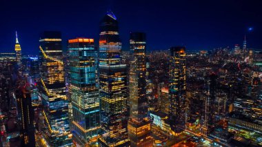 Geceleyin New York 'un engin panoramasını iflasa sürükledi. Karanlık nehrin şehri geçtiği ışıklarda muhteşem şehir manzarası. Üst görünüm.