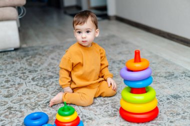 Küçük çocuk evde yerde oyuncaklarla oynuyor..