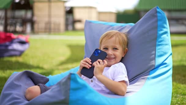 Καυκάσιο Ξανθό Μικρό Παιδί Χαμογελάει Κρατώντας Χαρούμενα Τηλέφωνο Στα Χέρια — Αρχείο Βίντεο