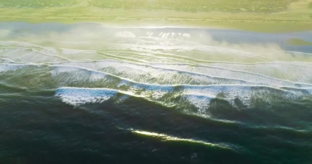 白色的泡沫般的小浪花在沙滩上飞溅 明亮的阳光照亮了大海的海岸 顶部视图 — 图库视频影像