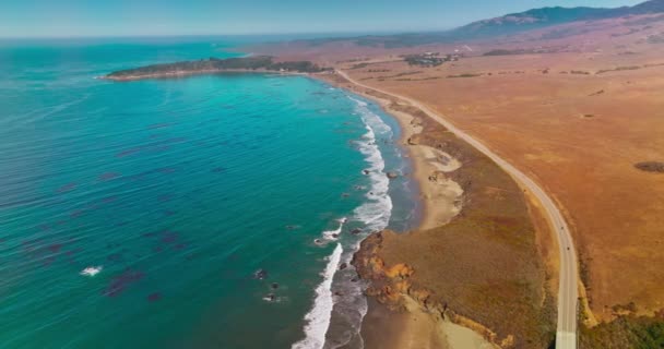 乾燥した砂漠は青い海に囲まれた土地です カリフォルニア州モロ湾の海岸線を通るハイウェイ トップビュー — ストック動画