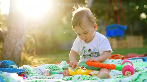 可爱可爱的小男孩在户外玩格子花 漂亮的孩子感兴趣地触摸着明亮的玩具 背景下明亮的阳光 — 图库视频影像