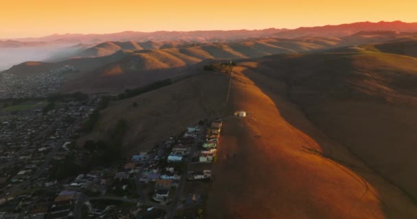 山の麓にある美しい居心地の良い街 太陽を設定するビームで裸の丘の素晴らしいパノラマ エアリアルビュー — ストック動画